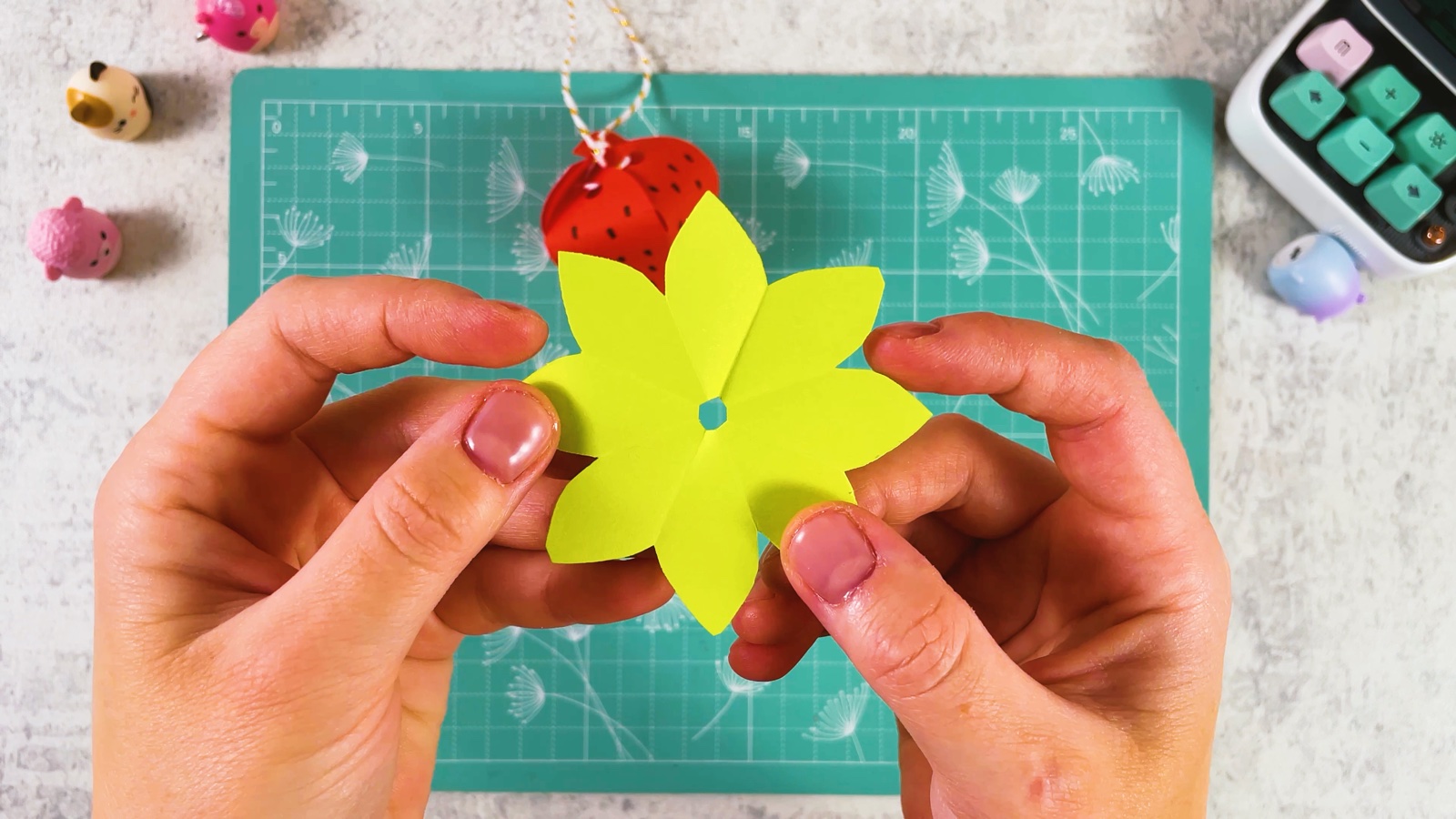 Opening the green paper into a star of pointy leaves with a hole in the centre
