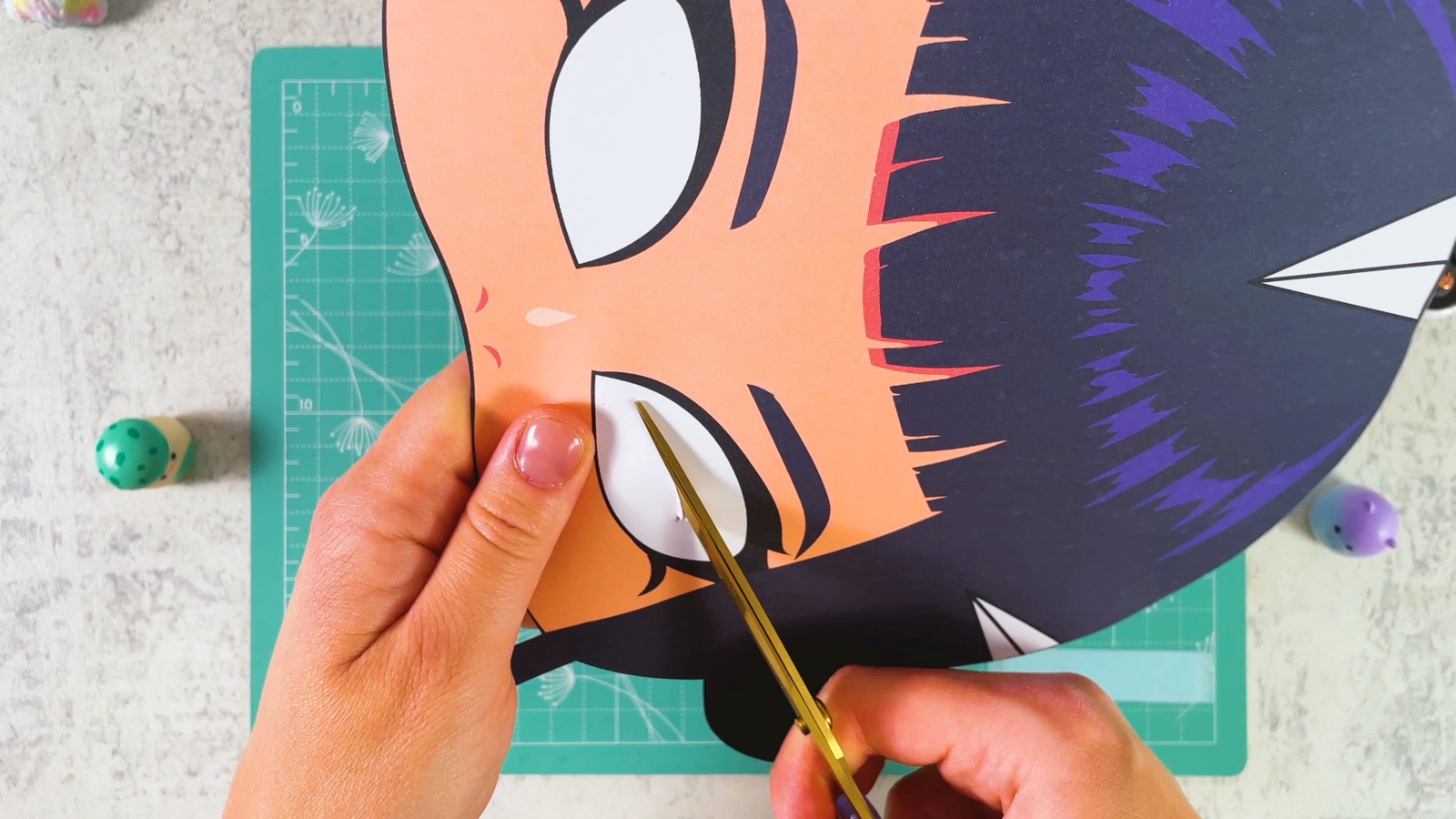 Cutting out the white eye hole of the paper mask with gold scissors