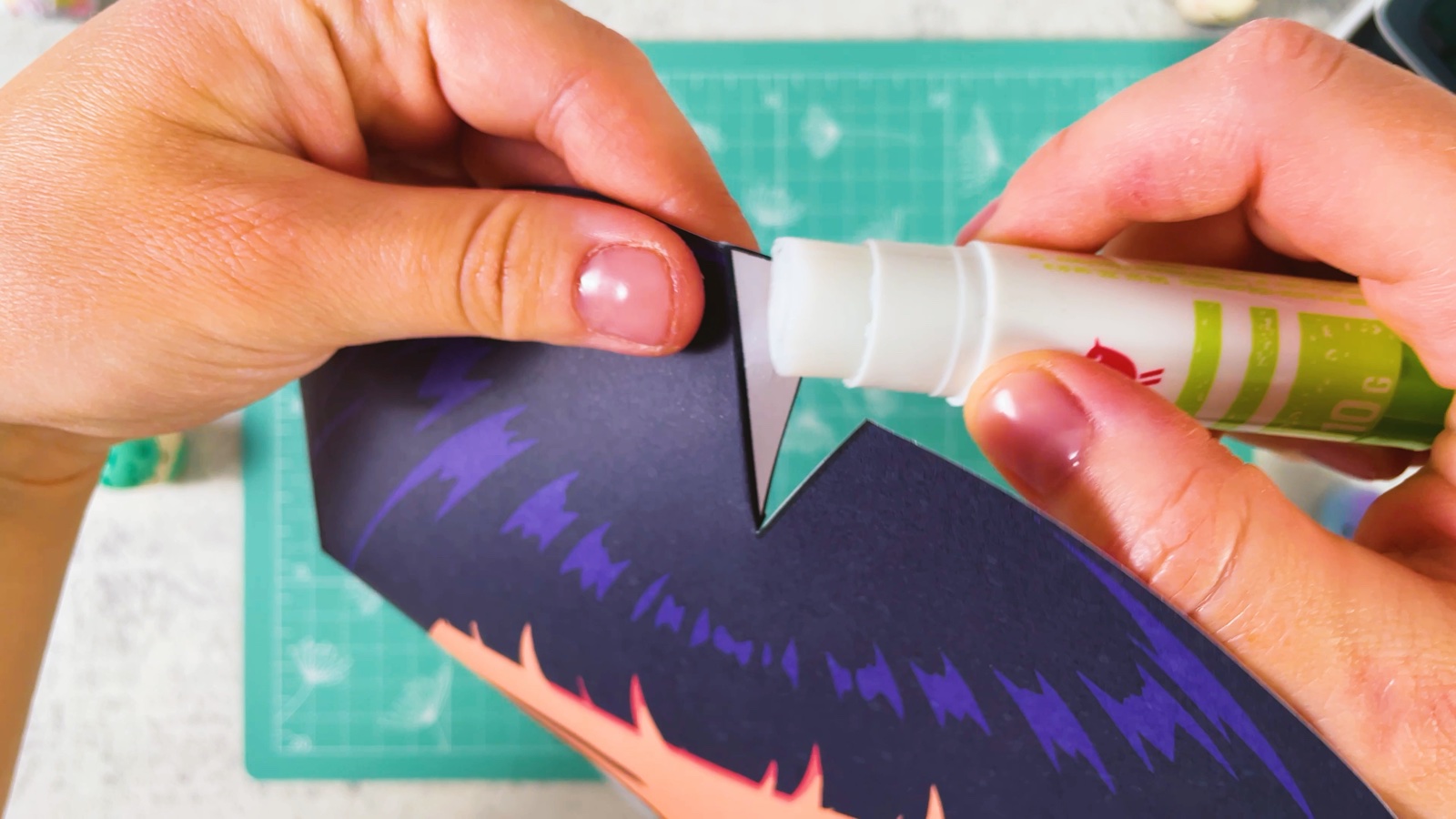 Putting glue on the white triangle in the hair with a glue stick