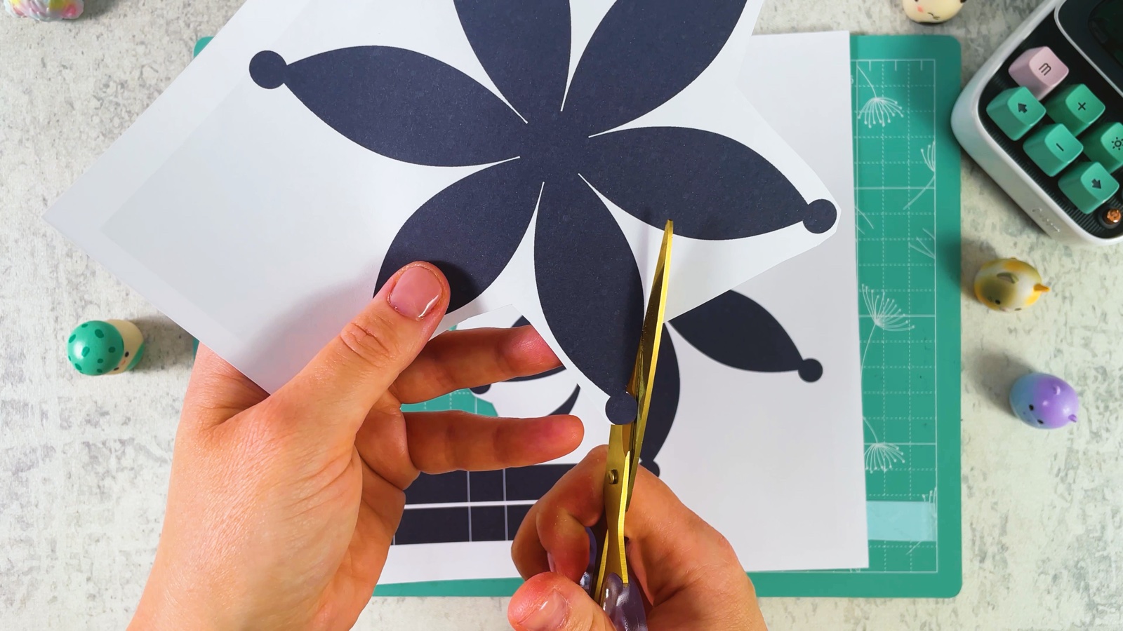 Cutting out a dark six-petal flower from the printed page