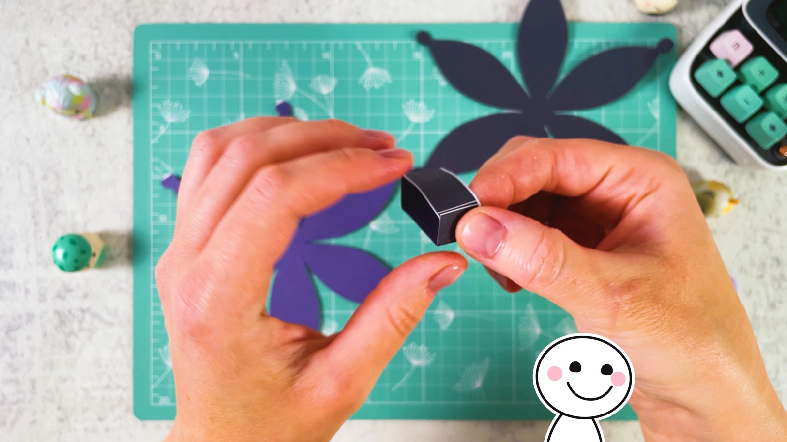 Holding the folded strip, now a tiny square paper box