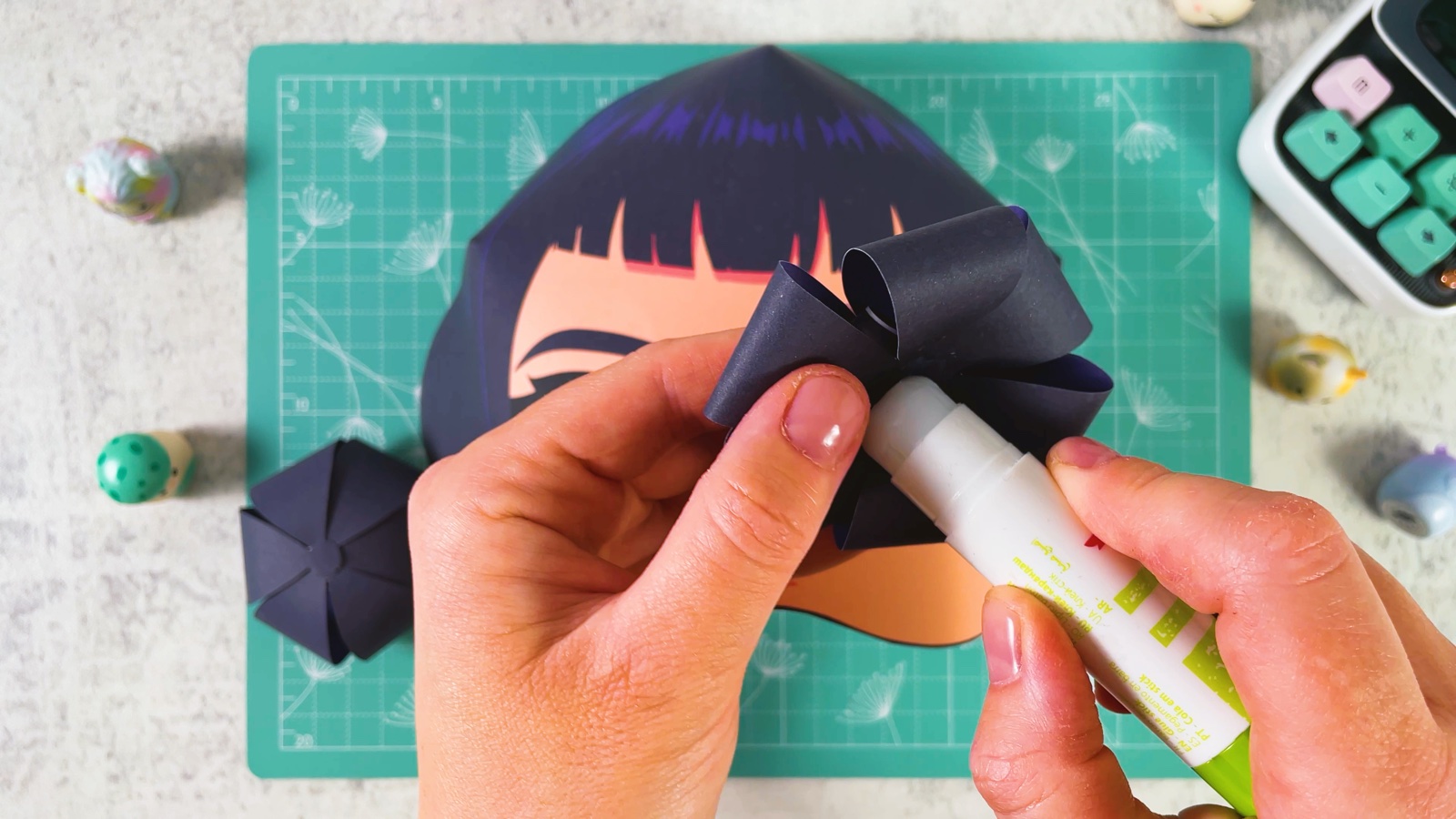 Putting glue on the bottom of a paper bun with a glue stick